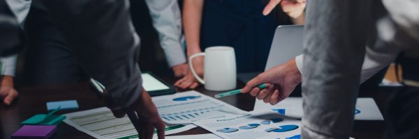 Millennial Asia businessmen and businesswomen meeting brainstorming ideas about new paperwork project colleagues working together planning success strategy enjoy teamwork in small modern night office.